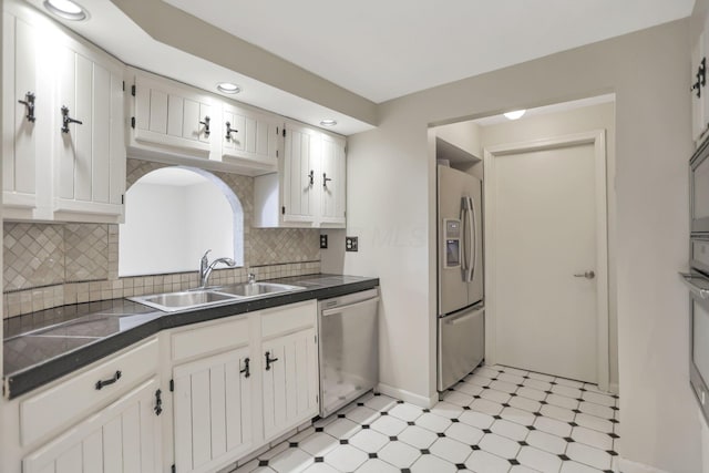 kitchen with backsplash, sink, white cabinets, and appliances with stainless steel finishes