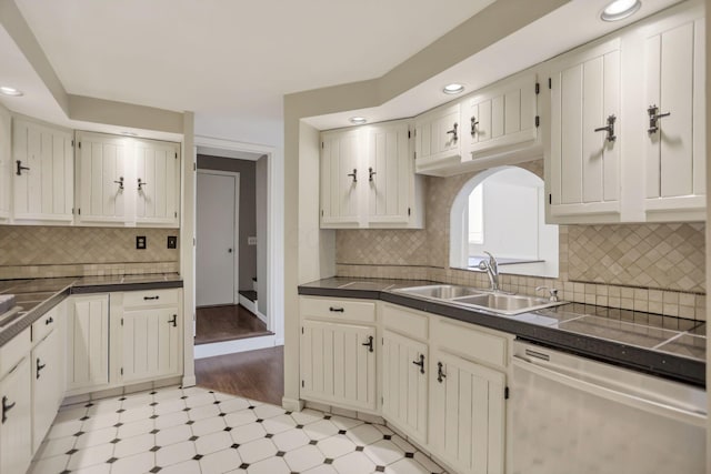 kitchen featuring decorative backsplash, dishwasher, sink, and light wood-type flooring