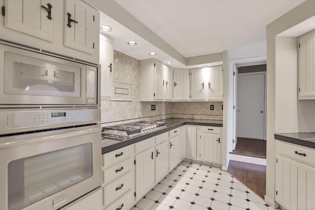 kitchen with tasteful backsplash, white cabinets, light wood-type flooring, and stainless steel gas stovetop