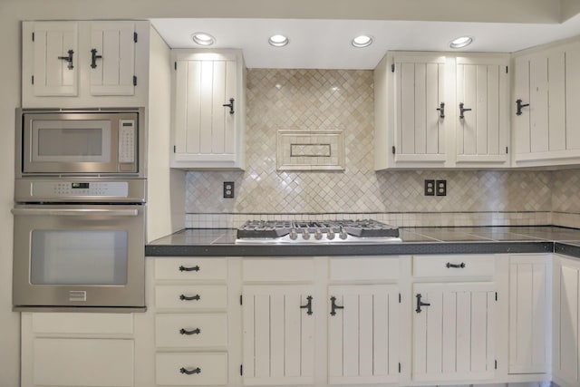 kitchen with tasteful backsplash, white cabinets, and appliances with stainless steel finishes