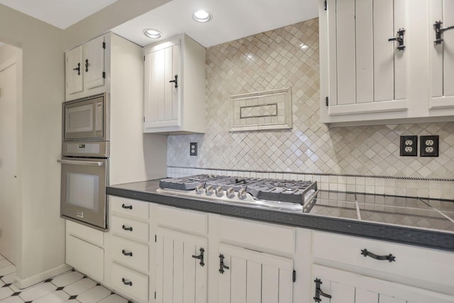 kitchen with decorative backsplash, white cabinetry, light tile patterned flooring, and stainless steel appliances