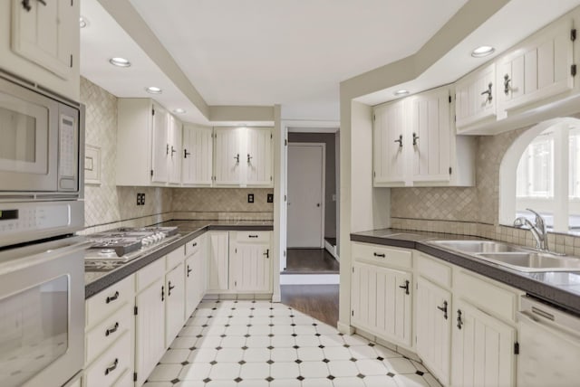 kitchen with sink, light hardwood / wood-style flooring, backsplash, white appliances, and white cabinets