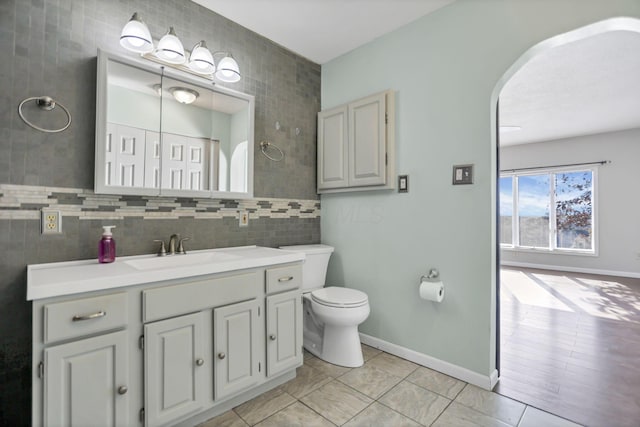 bathroom featuring vanity, toilet, and tile walls