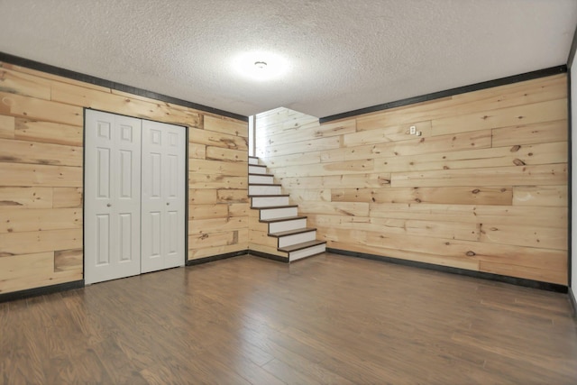 basement featuring wood walls, dark wood-type flooring, and a textured ceiling