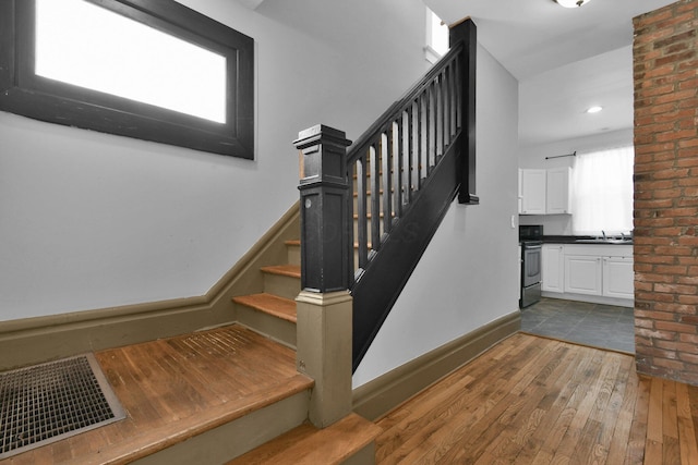 stairs with hardwood / wood-style floors, a healthy amount of sunlight, and sink