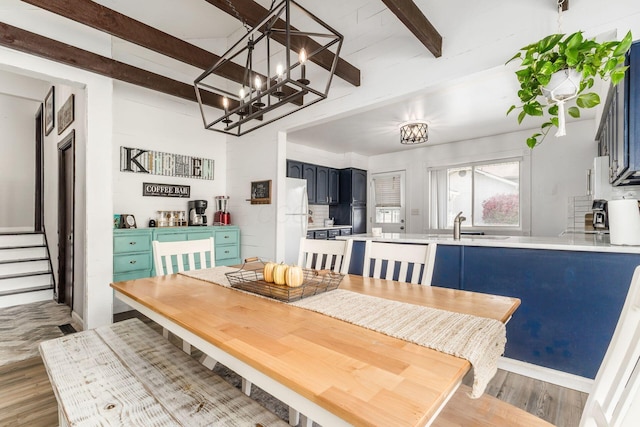 dining space with beam ceiling and light hardwood / wood-style flooring