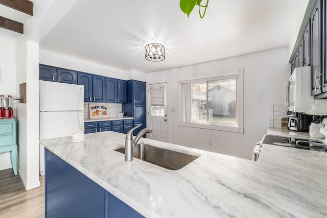 kitchen with blue cabinetry, light hardwood / wood-style floors, kitchen peninsula, and sink