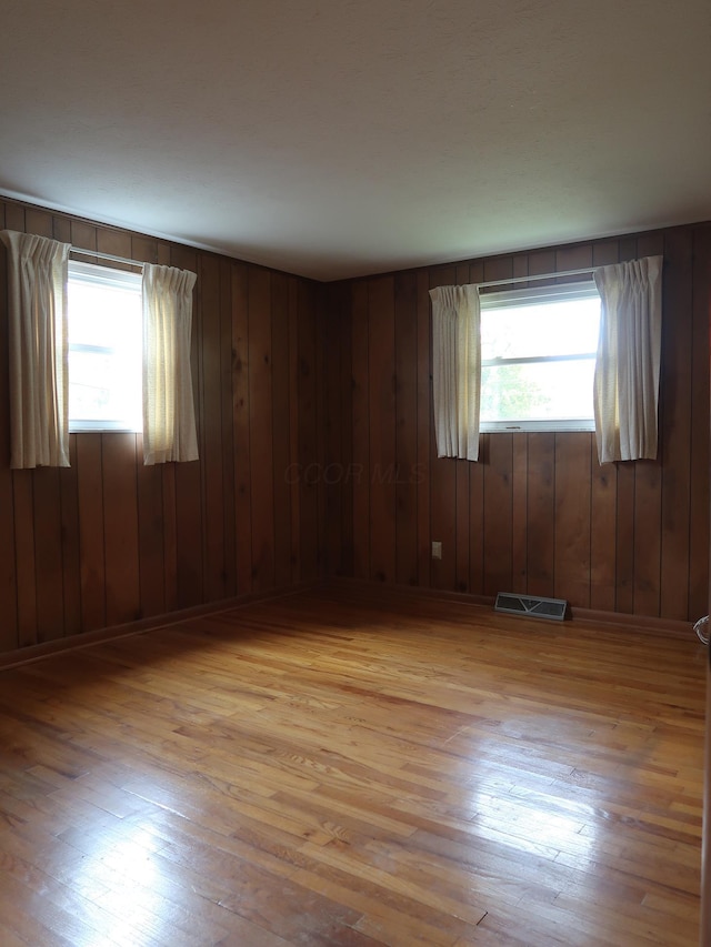 spare room with wooden walls and light hardwood / wood-style flooring