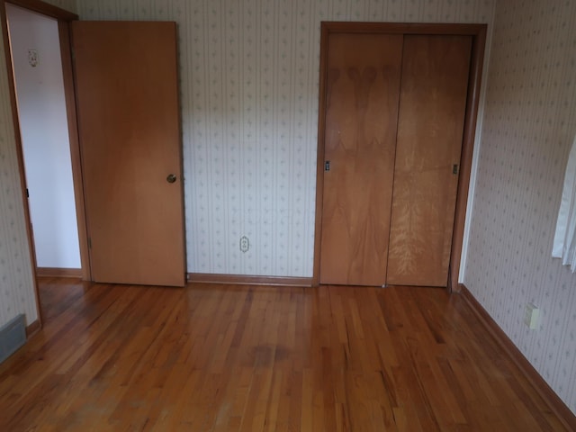 unfurnished bedroom with wood-type flooring and a closet