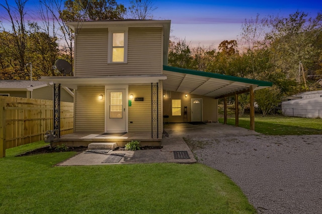 back house at dusk with a yard and a carport