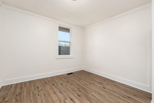 spare room featuring wood-type flooring and a textured ceiling