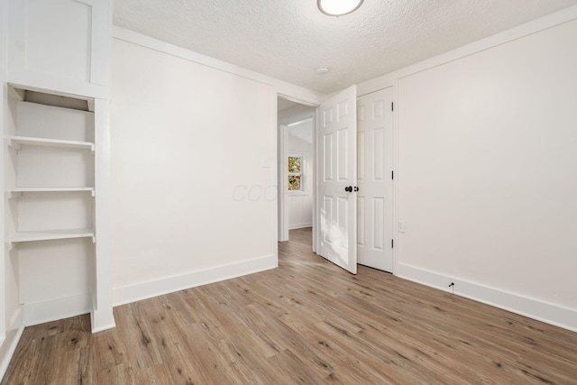 unfurnished bedroom with light hardwood / wood-style flooring and a textured ceiling