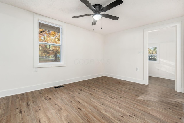 unfurnished room with a textured ceiling, hardwood / wood-style flooring, plenty of natural light, and ceiling fan