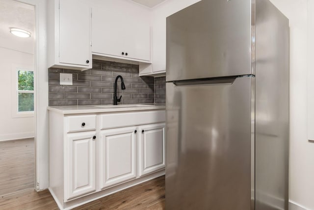 kitchen with stainless steel refrigerator, sink, white cabinets, and hardwood / wood-style flooring