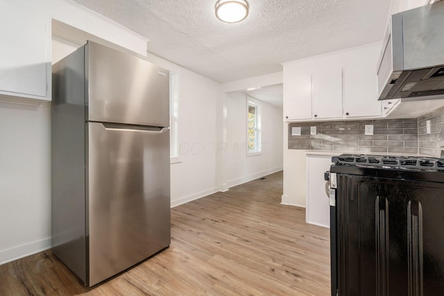 kitchen with backsplash, light wood-type flooring, a textured ceiling, white cabinetry, and stainless steel appliances