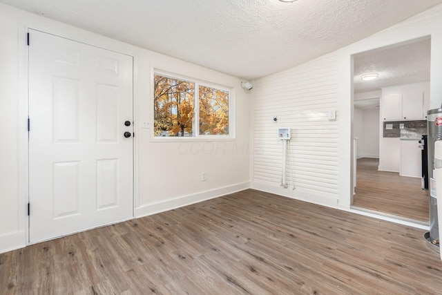 entrance foyer with a textured ceiling, light hardwood / wood-style flooring, and vaulted ceiling