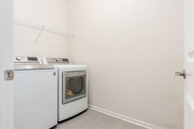 clothes washing area featuring light tile patterned flooring and washing machine and clothes dryer