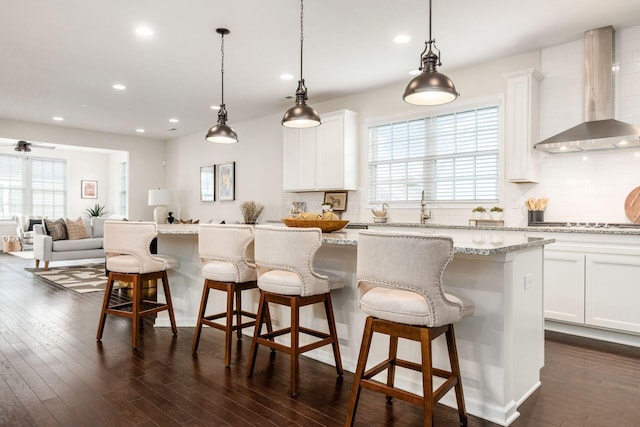 kitchen with a center island, white cabinetry, a wealth of natural light, and wall chimney exhaust hood