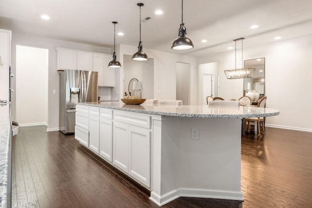 kitchen with white cabinets, a large island, stainless steel fridge with ice dispenser, and decorative light fixtures