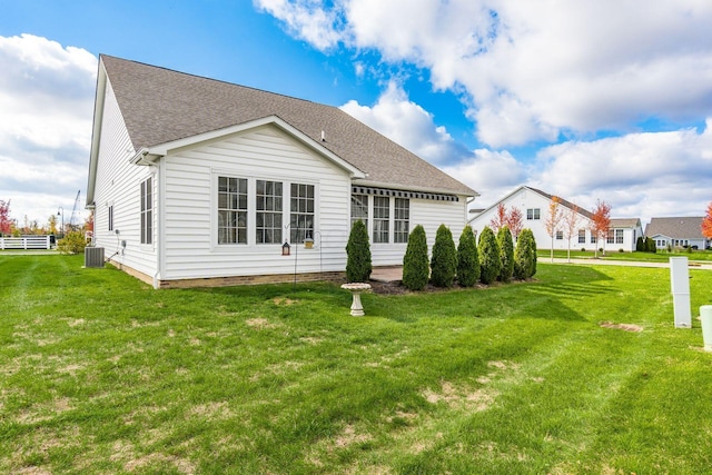 rear view of property with a lawn and central air condition unit