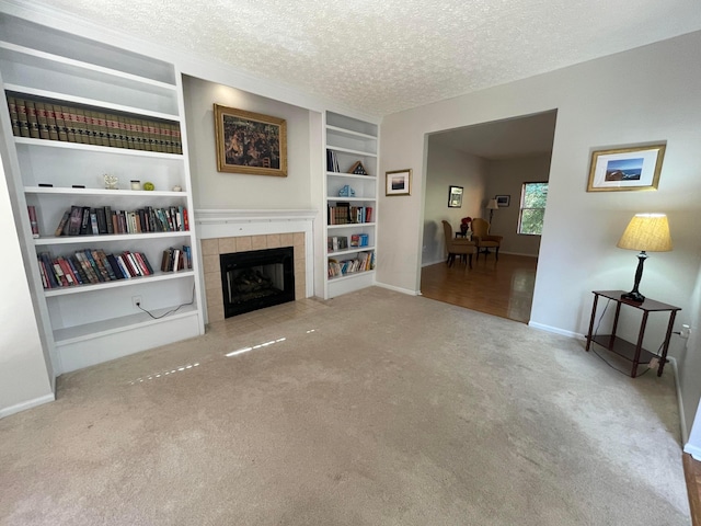 living room featuring a fireplace, light colored carpet, a textured ceiling, and built in shelves