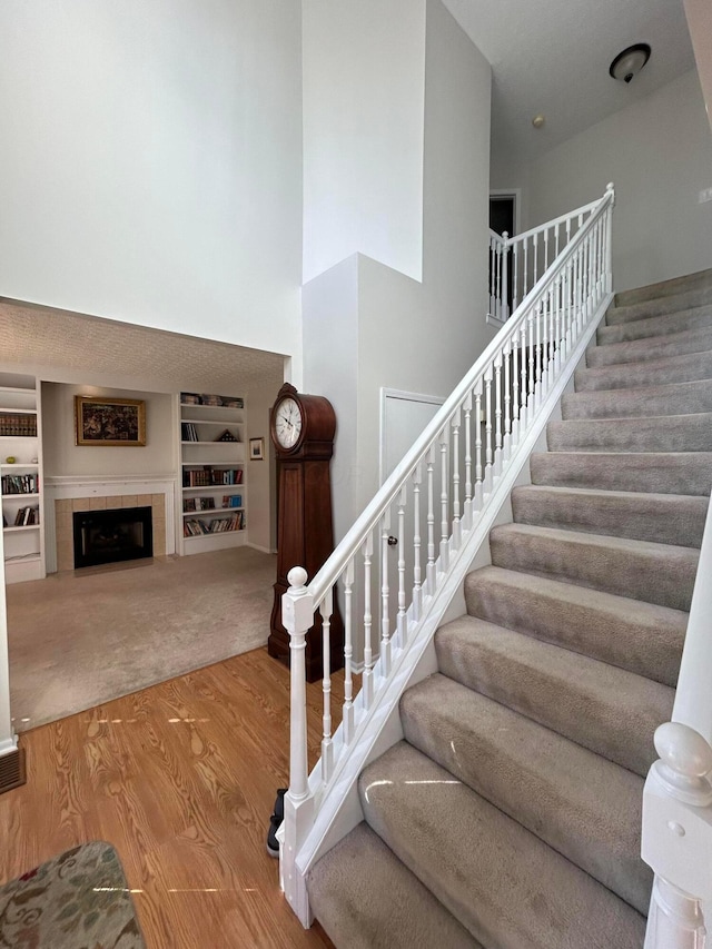 stairs with a fireplace, hardwood / wood-style floors, and built in shelves