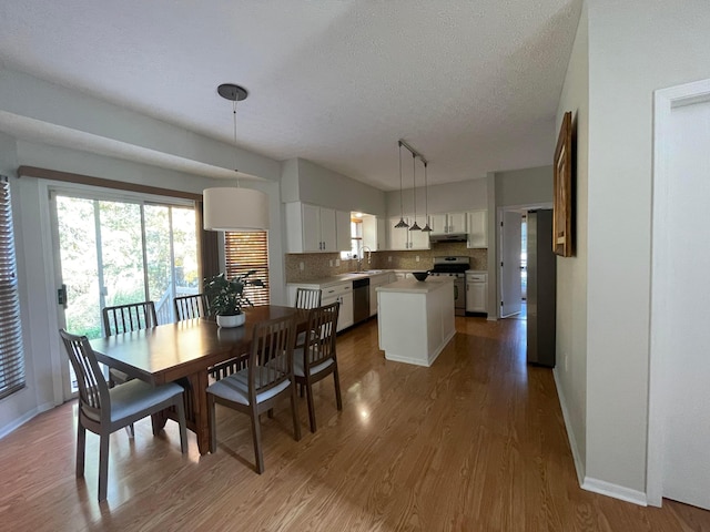 dining space with hardwood / wood-style floors, a textured ceiling, and sink