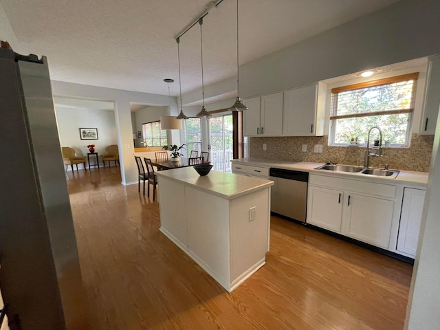 kitchen featuring stainless steel dishwasher, decorative light fixtures, white cabinetry, and sink