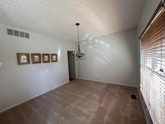 unfurnished dining area featuring carpet floors, a textured ceiling, and an inviting chandelier