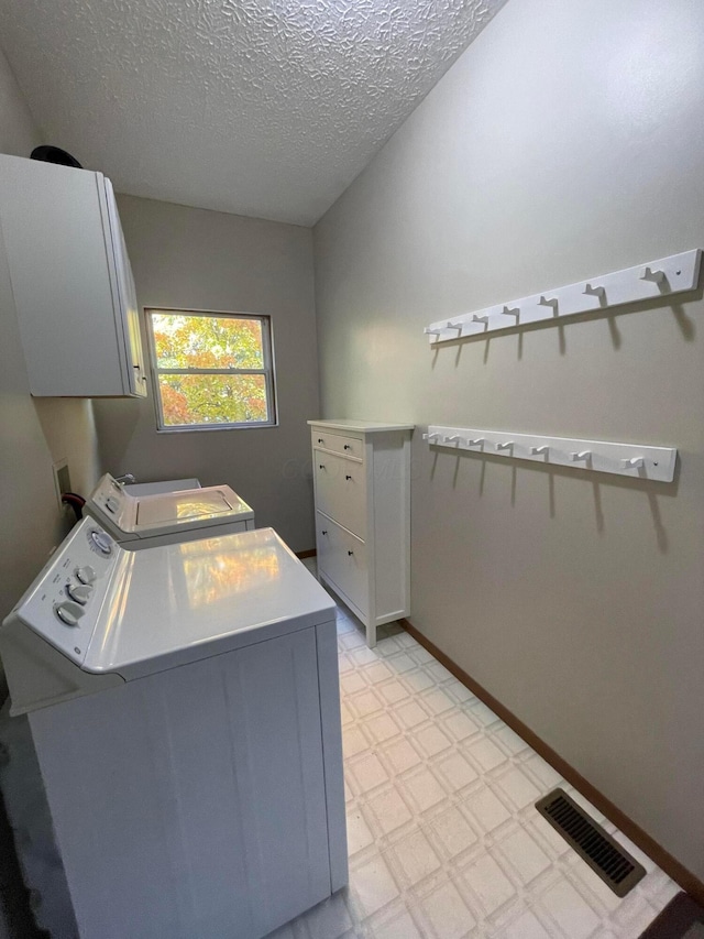 washroom with separate washer and dryer, cabinets, and a textured ceiling