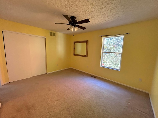 unfurnished bedroom featuring ceiling fan, carpet floors, a textured ceiling, and a closet