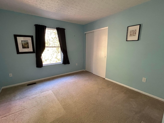 spare room featuring carpet floors and a textured ceiling