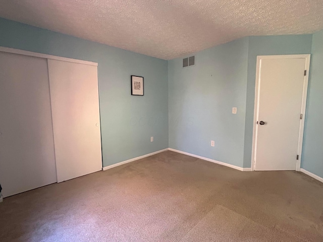 unfurnished bedroom featuring a textured ceiling, carpet floors, and a closet