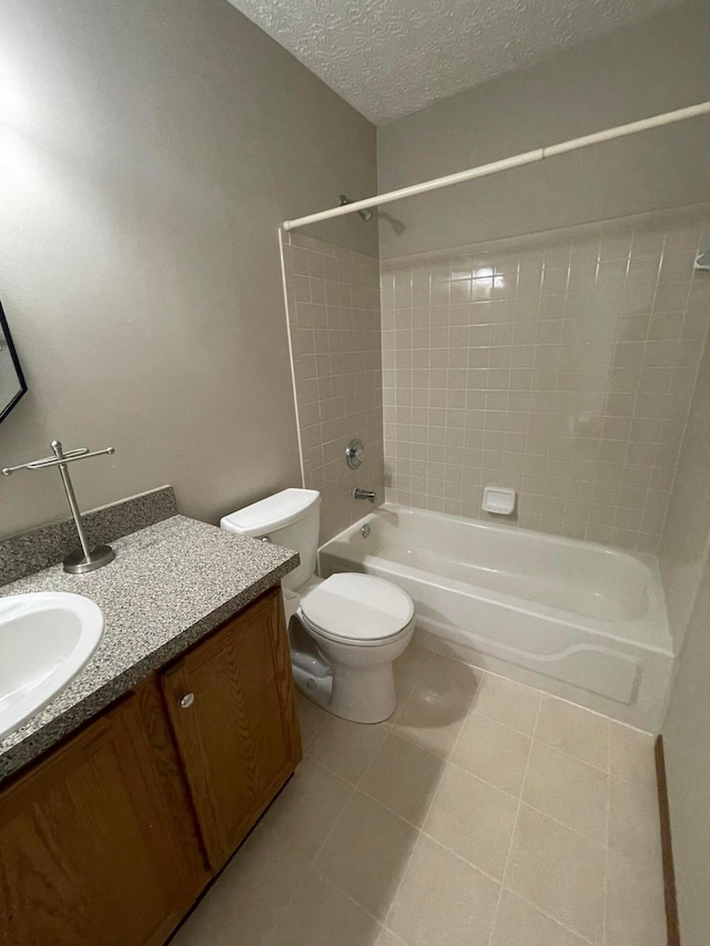 full bathroom with vanity, tile patterned floors, tiled shower / bath combo, toilet, and a textured ceiling