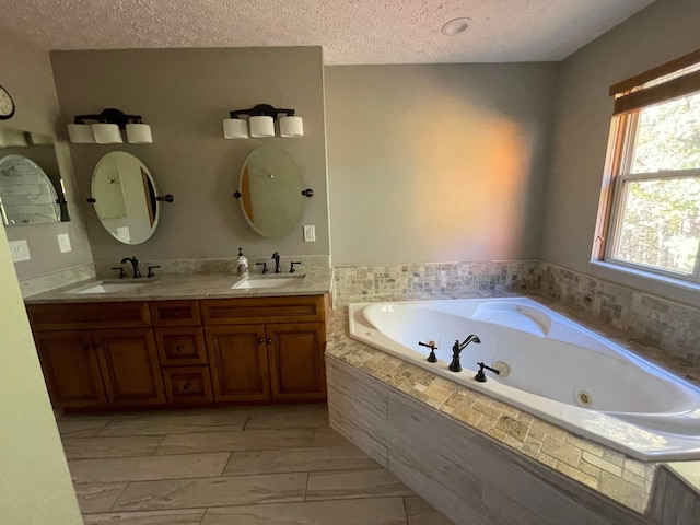 bathroom featuring tiled bath, vanity, and a textured ceiling