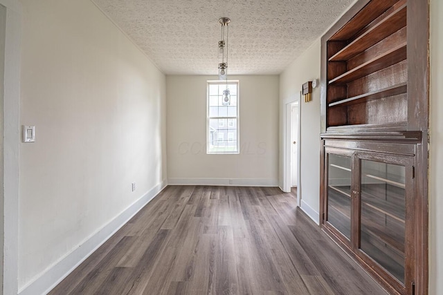 unfurnished dining area with dark hardwood / wood-style flooring and a textured ceiling