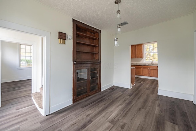 unfurnished living room with dark hardwood / wood-style flooring, a textured ceiling, and sink