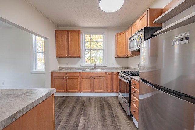 kitchen with dark wood-type flooring, sink, stainless steel appliances, and a textured ceiling