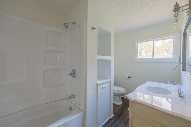 full bathroom featuring vanity, wood-type flooring, a textured ceiling, toilet, and shower / bathing tub combination