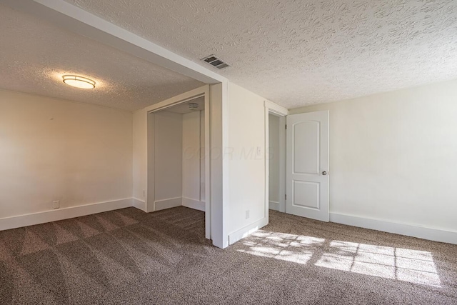 unfurnished bedroom with a textured ceiling, dark carpet, and a closet