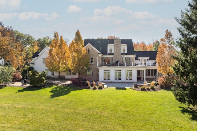 back of property featuring a balcony, a patio area, a yard, and french doors