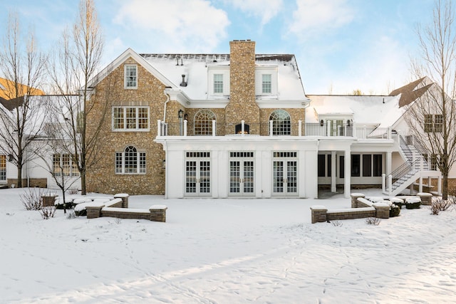 snow covered property featuring a balcony and french doors