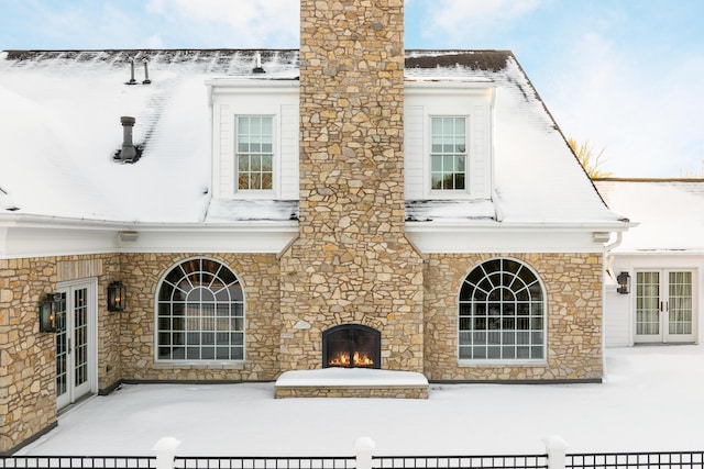 snow covered rear of property with an outdoor fireplace