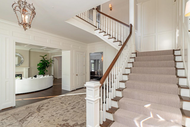 staircase featuring an inviting chandelier and ornamental molding