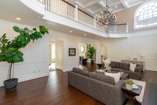 living room featuring coffered ceiling, beamed ceiling, a high ceiling, and dark wood-type flooring