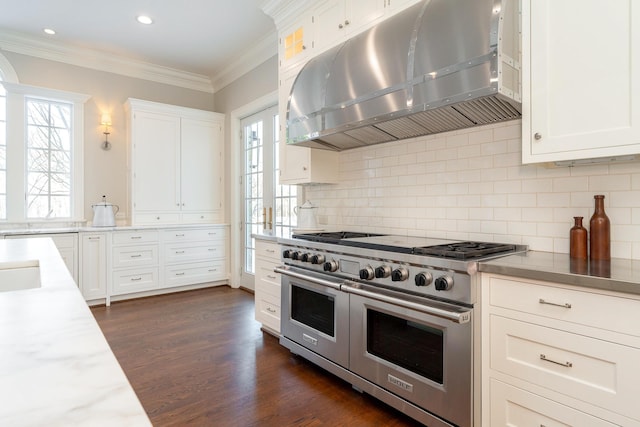 kitchen featuring range hood, range with two ovens, decorative backsplash, and white cabinetry