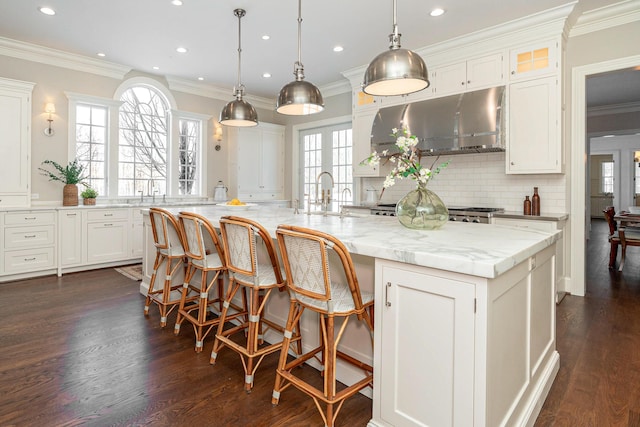 kitchen featuring backsplash, pendant lighting, ventilation hood, and a spacious island