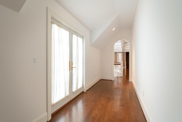 hallway featuring vaulted ceiling, a wealth of natural light, and dark hardwood / wood-style flooring