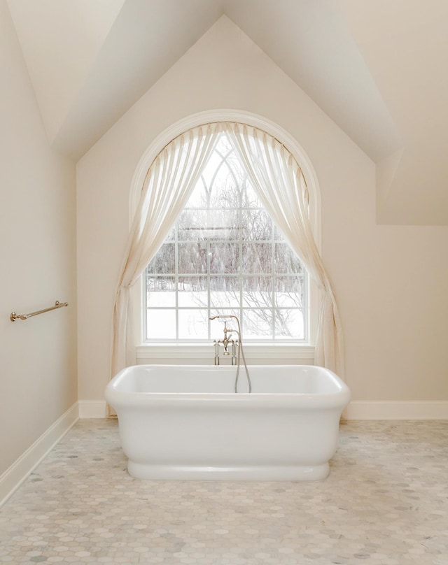 bathroom featuring a bath and lofted ceiling