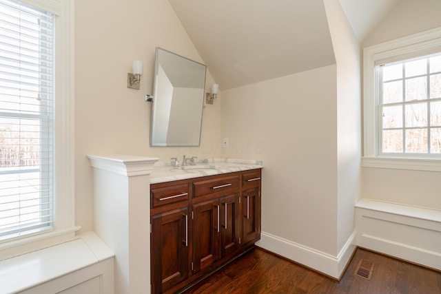 bathroom featuring hardwood / wood-style floors, plenty of natural light, lofted ceiling, and vanity